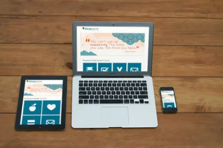 A desk with a computer, tablet, and mobile phone showing the Bluespire Holiday website.